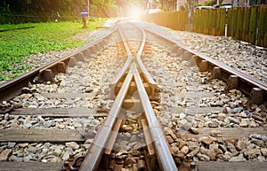 Train tracks on gravel, two of railways tracks merge  with sunset background, concept of success