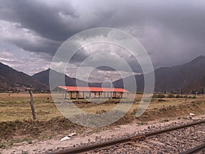 Train tracks and yellow meadow with mountain photo