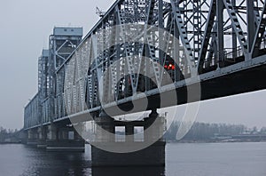 The train is traveling over a bridge over a river in thick fog. Gray background, color photo. Mystical picture