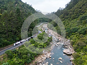 a train is traveling on the track near a forest area, Karangahake Gorge, New Zealand