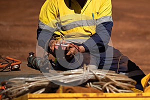 Trained competent electrician setting holding red electricity tester and conducting monthly safety testing tagging power grinder