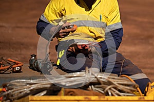 Trained competent electrician setting holding red electricity tester while conducting safety inspecting monthly tag