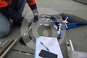 Trained safety auditor wearing black safety glove inspecting using spanner tensioning industrial working at heights lifeline photo