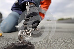 Trained safety auditor wearing black safety glove using spanner tensioning industrial rope access working at heights fall arrest