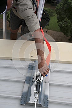 Trained worker clipping industrial hook connected fall arrest shock absorbing safety lanyard device into first man point