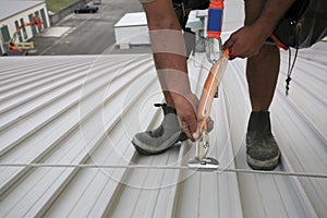 Trained worker inspecting fall arrest height safety device la roof lifeline steel cable system nyard attached