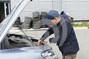 Trainee auto mechanic works in a garage, outdoors. Automobile Repair Service Concept