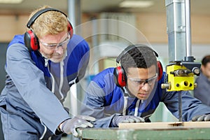 Trainee carpenter using band saw under supervision