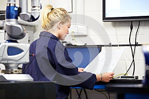 Trainee Engineer Studying Plans With CMM Arm In Foreground