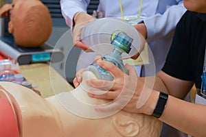 A trainee hold an oxygen mask with two hands with a nurse ventilventilating via ambubag