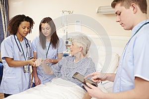 Trainee Nursing Staff By Female Patient's Bed In Hospital