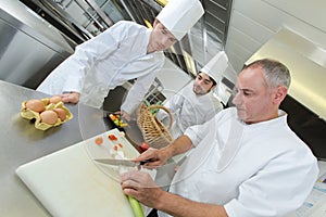 Trainees watching chef prepare vegetables