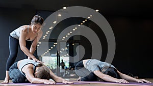 The trainer adjusts the correct posture for the student to learn yoga