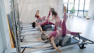 A trainer adjusts women on a reformer.