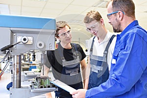 trainer and apprentice in technical vocational training at a drilling machine photo