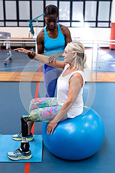 Trainer assisting disabled senior woman in sports center