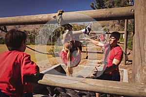 Trainer assisting a girl in obstacle course training