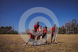 Trainer assisting kids in tug of war during obstacle course training