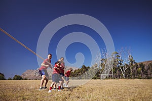 Trainer assisting kids in tug of war during obstacle course training