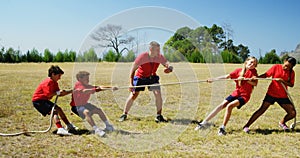 Trainer assisting kids in tug of war during obstacle course training