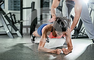 Trainer assisting a muscular woman on a plank position.