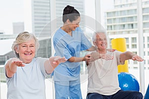 Trainer assisting senior couple in exercising