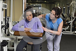 Trainer Assisting Senior Woman In Gym