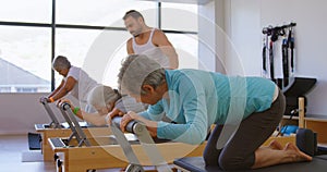 Trainer assisting senior women while performing yoga 4k