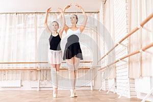 The trainer of the ballet school helps young ballerina perform different choreographic exercises.