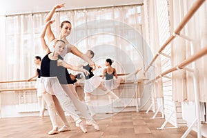 The trainer of the ballet school helps young ballerina perform different choreographic exercises.