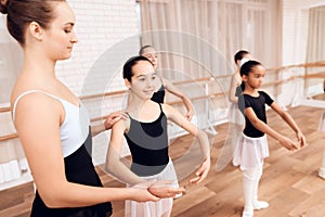 The trainer of the ballet school helps young ballerinas perform different choreographic exercises.