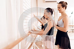 The trainer of the ballet school helps young ballerinas perform different choreographic exercises.