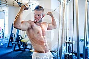 Trainer, bodybuilder working out the biceps and the abs in gym