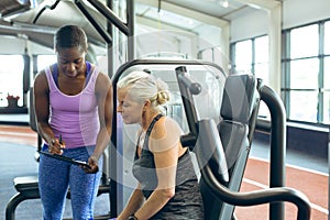 Trainer discussing over clipboard with active senior woman in fitness studio