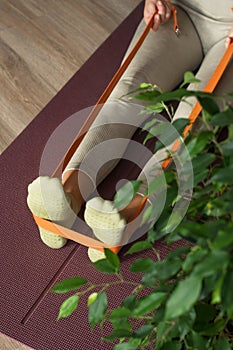 Trainer doing leg stretching exercises with orange fitness rubber bands. Fitness trainer doing exercises in pilates yoga
