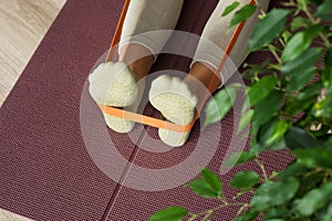 Trainer doing leg stretching exercises with orange fitness rubber bands. Fitness trainer doing exercises in pilates yoga