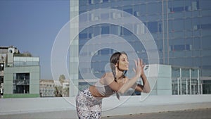 Trainer doing standing forward bend pose on street. Girl stretching body on mat