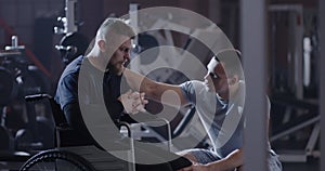 Trainer encouraging wheelchair man in gym