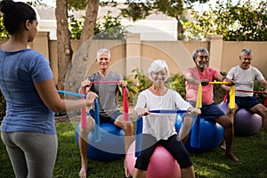 Trainer guiding senior people while exercising with ribbons and balls