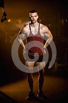 The trainer in the gym, shows his muscles, athletic man