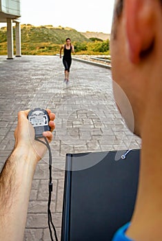 Trainer hand using chronometer to timing woman