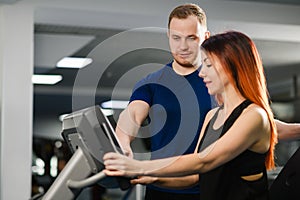 Trainer help woman with gym sports machine