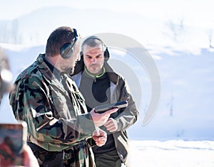 Trainer helping young person to aim with handgun at combat training