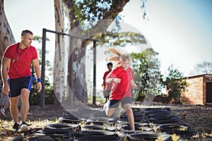 Trainer instructing kids during tyres obstacle course training