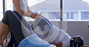 Trainer instructing senior women while performing yoga 4k
