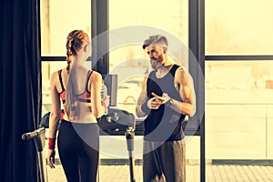 Trainer instructing trainee standing on treadmill in gym