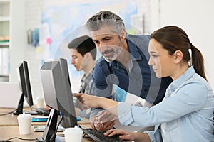 Trainer with interns working on desktop computer