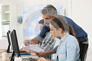 Trainer with interns working on desktop computer