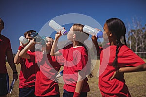 Trainer and kids drinking water in the boot camp