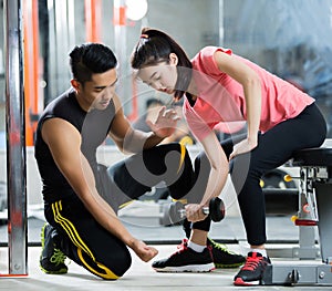 Trainer men are teaching Asian woman lifting a dumbbell. In the way they exercise